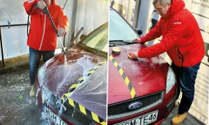Mężczyzna myje i woskuje samochód na myjni bezdotykowej. Najpierw spłukuje auto pianą, a potem nakłada wosk.
