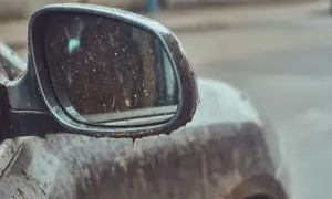 Błotniste lusterko boczne samochodu, które wygląda, jakby właśnie zakończyło się mycie auta w deszczu.