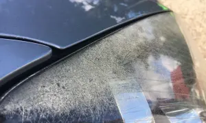Głębokie rysy na reflektorze samochodu, świadczące o jego zużyciu.