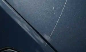 Drobne rysy na lakierze w kolorze obsidian, przypominające ślady po kamieniach na drodze.
