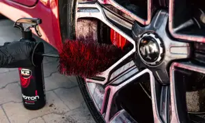 Szczotka do felg K2 Roton w akcji, podczas profesjonalnego **detailingu samochodu**. Czerwone włosie dociera do zakamarków, usuwając brud.