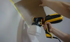 Malowanie sprayem w domu. Karton chroni sufit przed farbą z pistoletu.