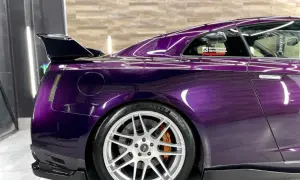 Sportowy Nissan GT-R w odcieniu **midnight purple**, z karbonowym spoilerem i felgami.