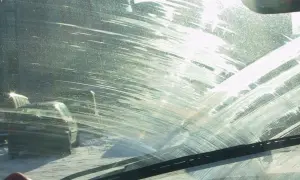 Widok przez brudną szybę z smugami po płynie do spryskiwaczy. Zastanawiasz się, czym wyczyścić wycieraczki samochodowe, by znów były skuteczne?