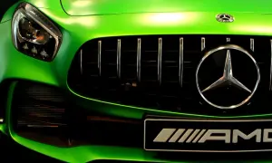 Zielony Mercedes AMG z błyszczącym chromem na grillu i emblematach.