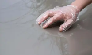 Ręka w rękawiczce dotyka błyszczącej powierzchni, przygotowując ją do nałożenia domowego wosku do samochodu.