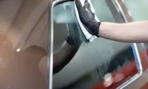 Rękawiczka z mikrofibry czyści zaparowaną szybę w aucie od środka.
