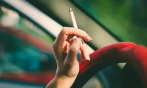 Dłoń trzymająca papierosa w aucie. Zastanawiasz się, jak pozbyć się zapachu papierosów z auta?