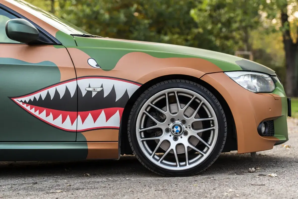 BMW z oklejoną maską i błotnikiem w kamuflażu i malowaniem w kształcie rekina. Avery Dennison zapewnił materiały do tej transformacji.