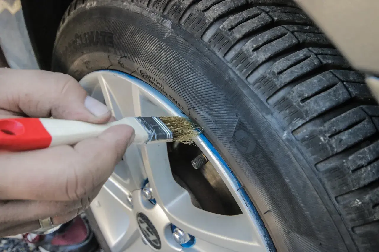 Ręczne malowanie felgi pędzlem, pokazujące zastosowanie gumy w sprayu do tuningu wizualnego opon.