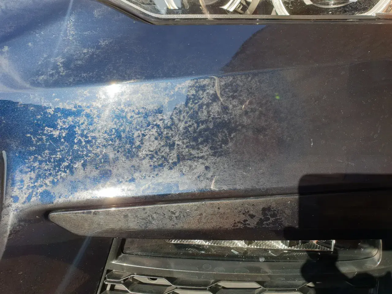 Matowe plamy na lakierze samochodowym, wyglądające jak nalot po wodzie lub chemikaliach, szpecą błyszczącą powierzchnię.