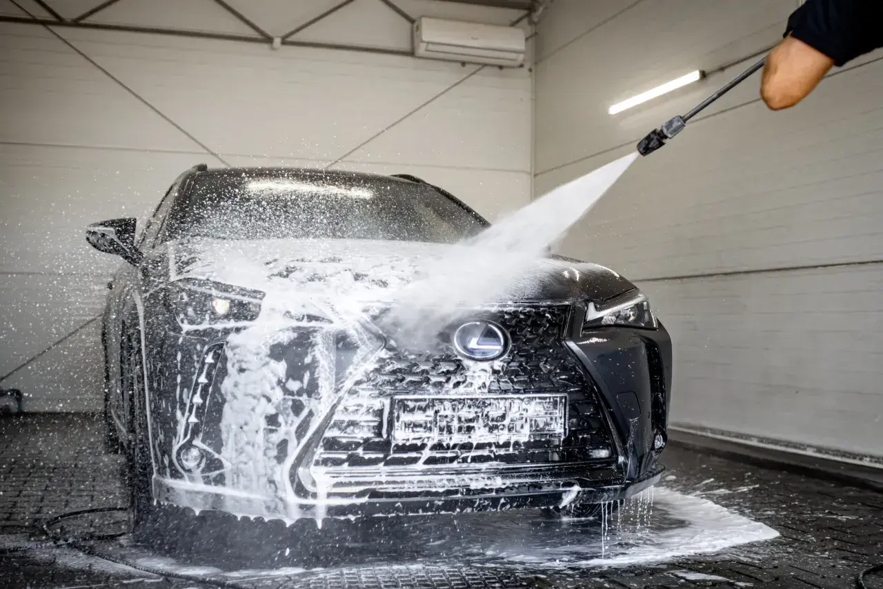 Czarny Lexus w myjni bezdotykowej. Woda i piana spływają po masce i grillu. Poznaj myjnia bezdotykowa triki, by Twój samochód lśnił!