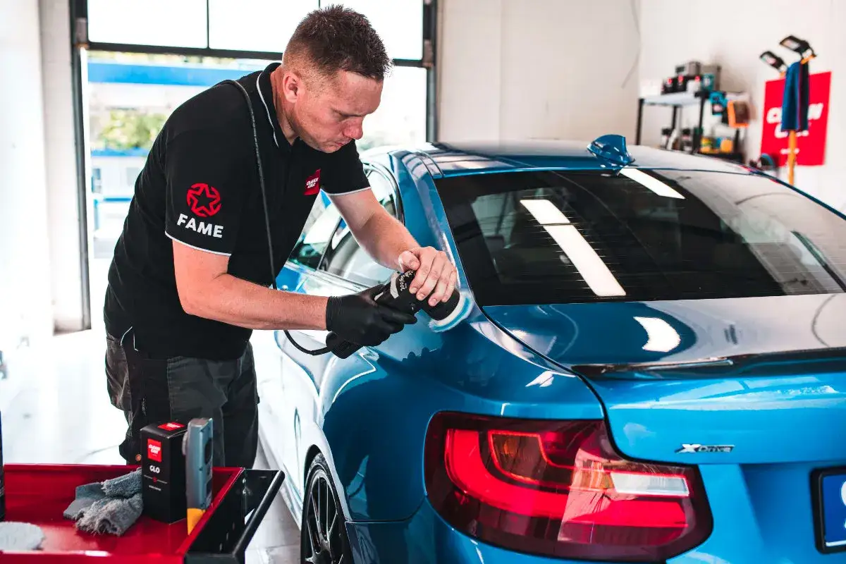 Profesjonalny detaling auta – mężczyzna poleruje niebieskie BMW, nadając mu idealny połysk.