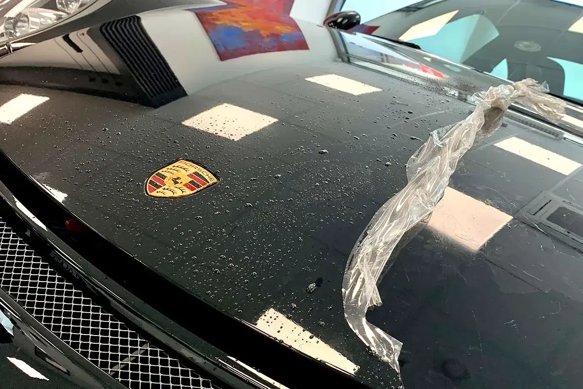 Klej po naklejce na czarnej masce Porsche. Krople wody i folia ochronna. Czym zmyć klej z naklejki?