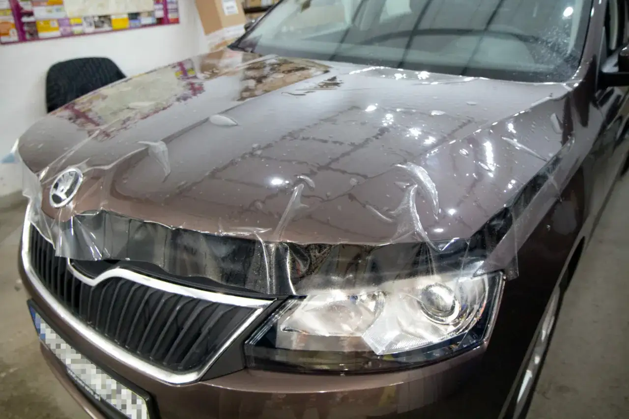 Brązowy samochód Skoda z nałożoną folią zabezpieczającą lakier na masce i błotnikach.