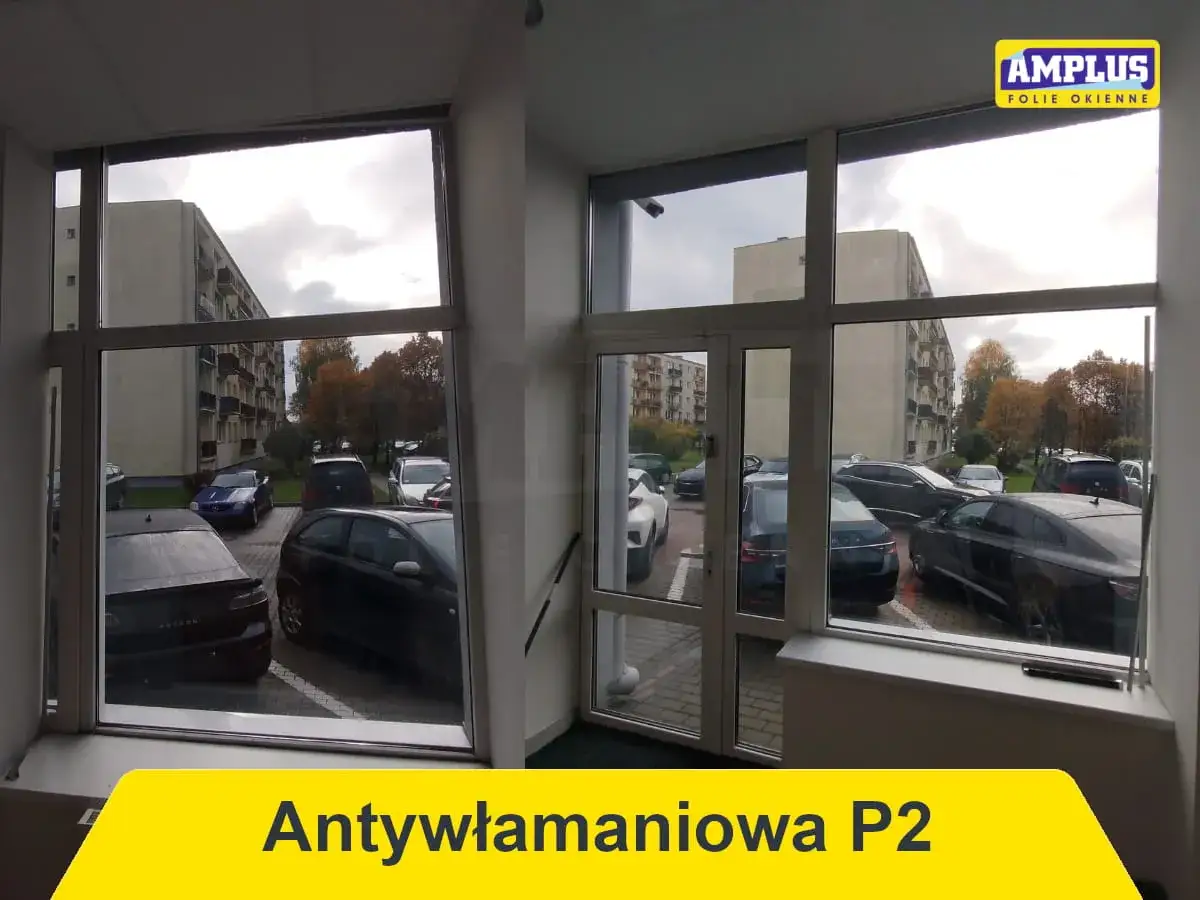 Folia antywłamaniowa P2 - warto zainwestować w bezpieczeństwo. Widok na parking i bloki mieszkalne przez okno z folią.