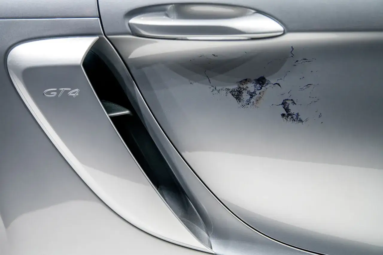 Schodzi lakier bezbarwny na srebrnym Porsche GT4. Uszkodzenie wygląda jak pęknięcia i odpryski. Jak naprawić?