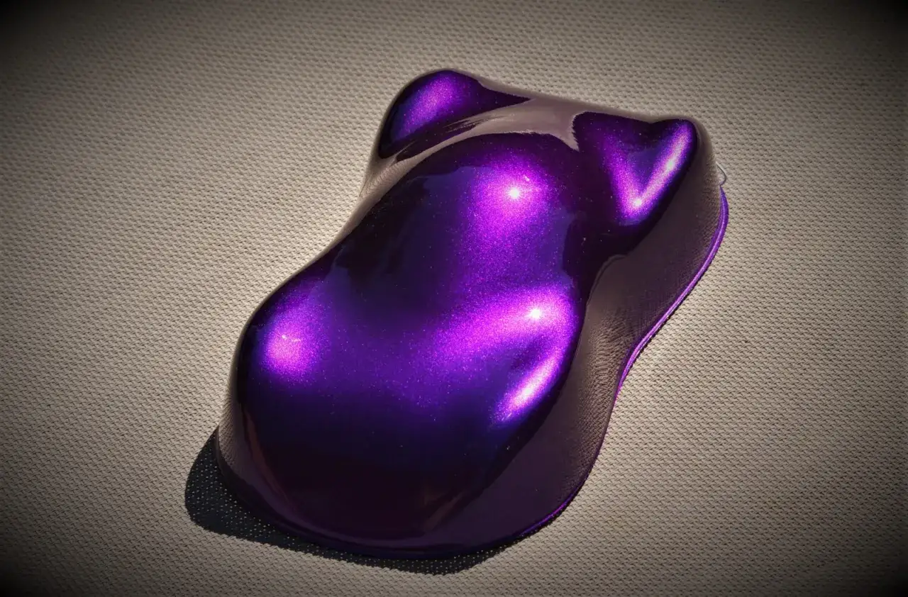 Próbka lakieru samochodowego w odcieniu midnight purple, lśniąca i metaliczna, na szarej powierzchni.