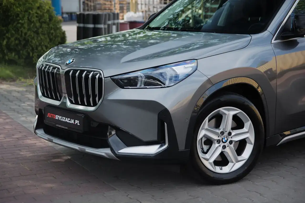 Nowy BMW X1 w eleganckim, grafitowym kolorze, z charakterystyczną atrapą chłodnicy i nowoczesnymi światłami.