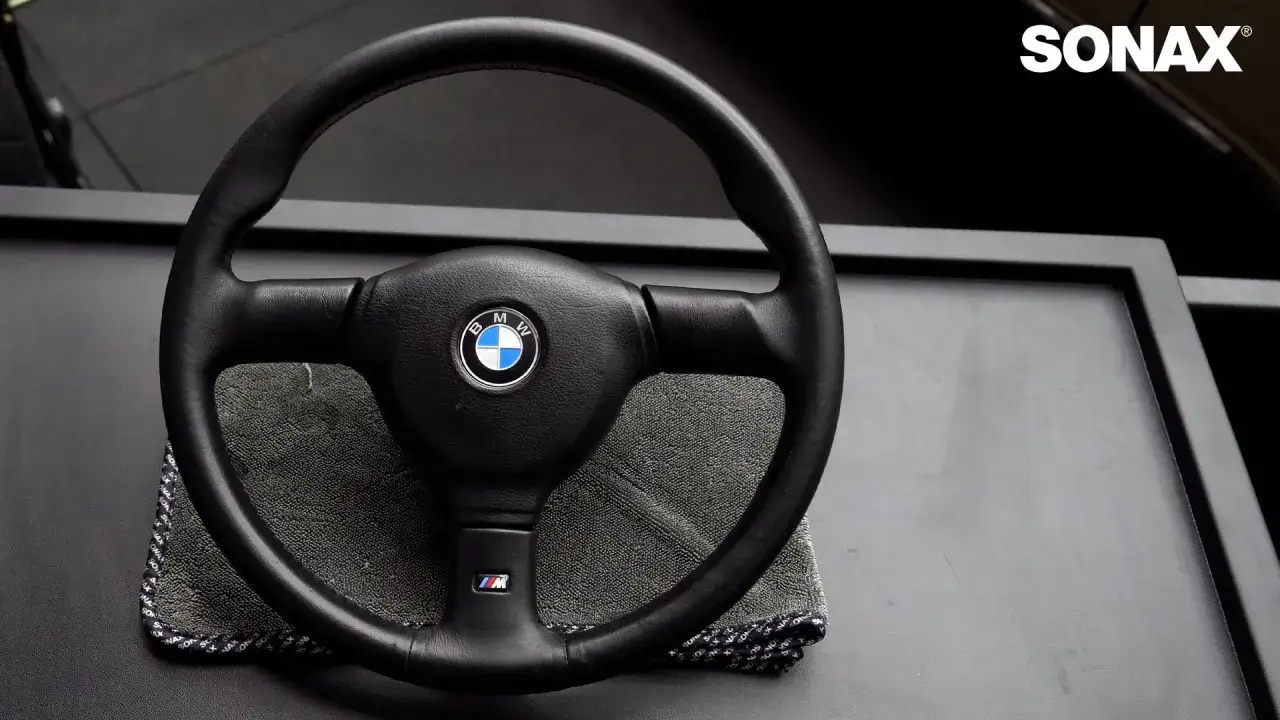 Skórzana kierownica BMW czeka na domowe sposoby na czyszczenie. Mikrofibra SONAX gotowa do akcji.
