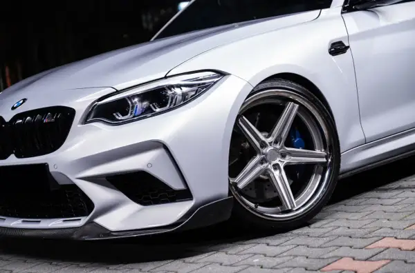Srebrne auto z chromowanymi felgami o wieloramiennym wzorze i niebieskimi zaciskami hamulcowymi. Idealne felgi do srebrnego auta? Te wyglądają świetnie!
